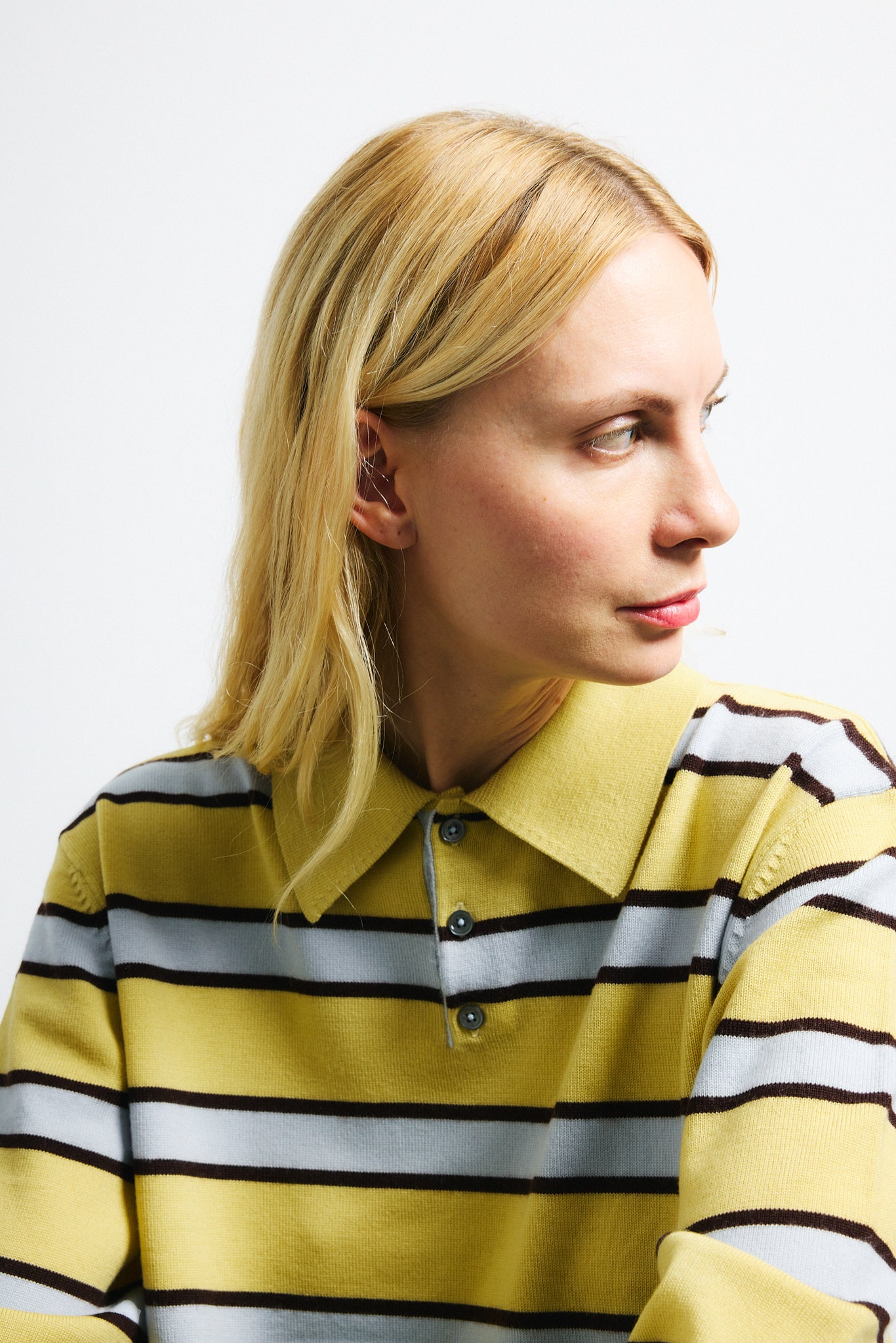 Link to "Ryan" sweater. Image is of a female model wearing yellow and grey striped polo with green sequin midi skirt. 