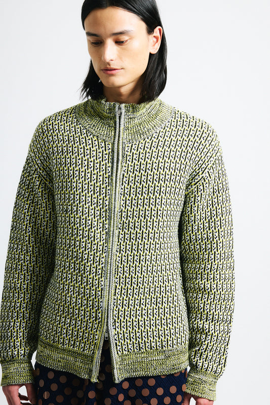 Link to "Malo" zip-up. Image is of a male model wearing yellow mixed stitch double zip up high-collar chunky sweater and navy blue/chocolate paillette knit shorts.