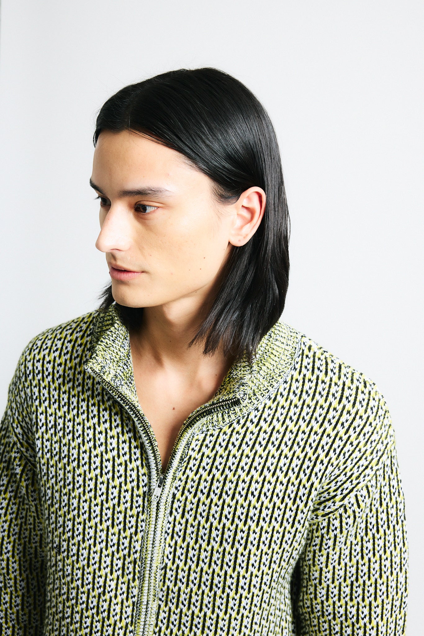 Link to "Malo" zip-up. Image is of a male model wearing yellow mixed stitch double zip up high-collar chunky sweater and navy blue/chocolate paillette knit shorts.