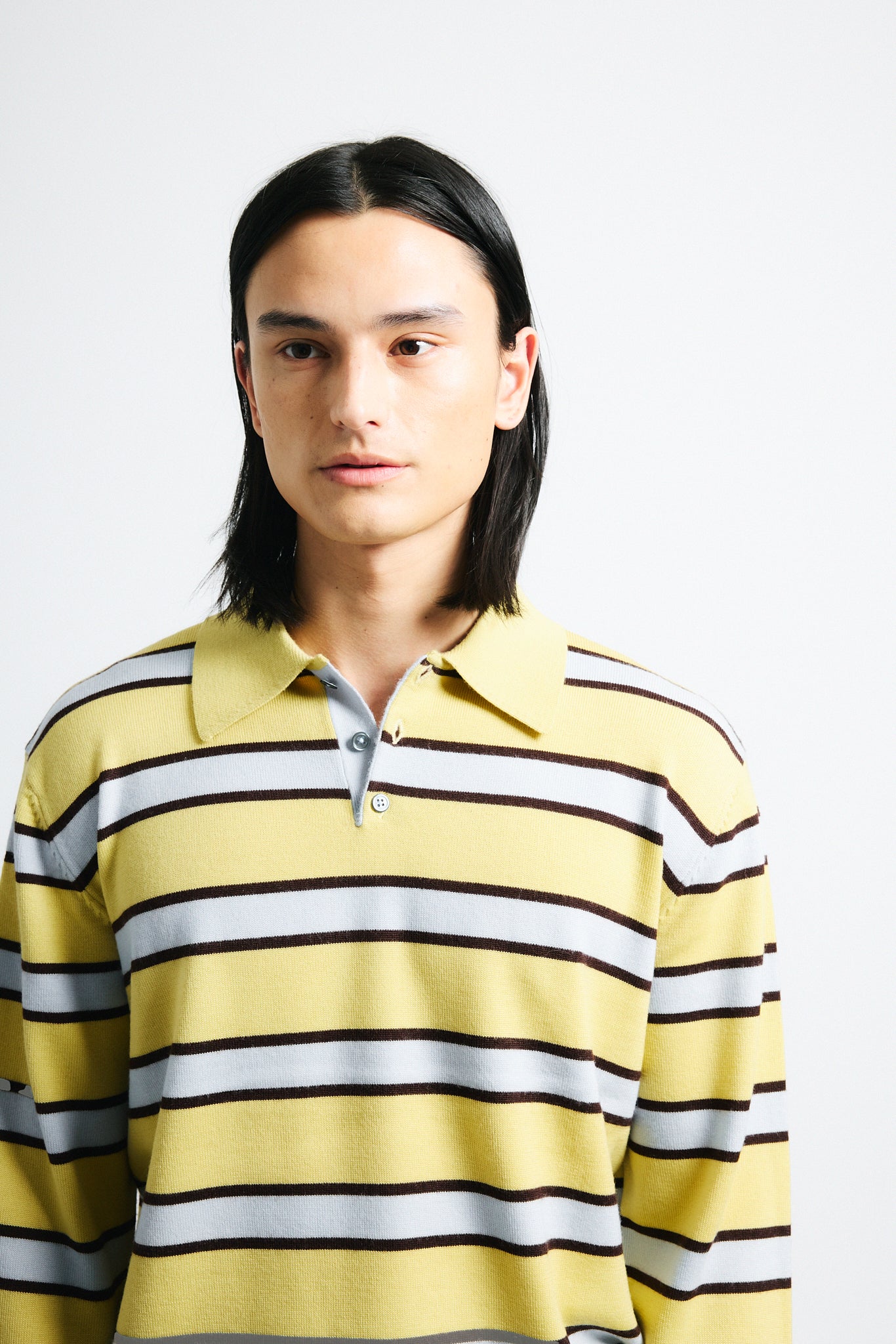 Link to "Ryan" sweater. Image is of a male model wearing yellow and grey striped polo with black shorts.