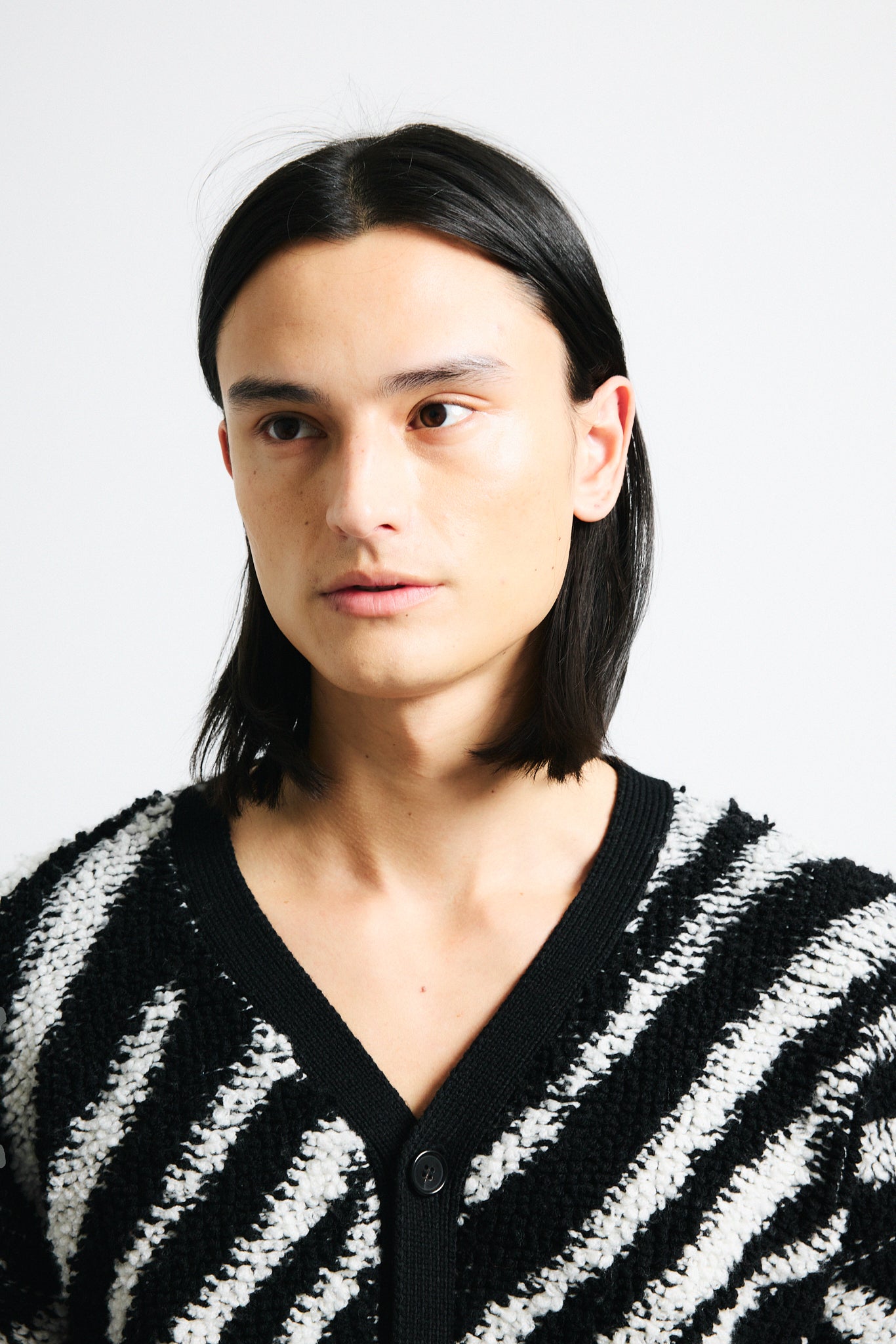 Link to "Christian" cardigan. Image is of a male model wearing "oil spill"/"zebra" print fuzzy v-neck cardigan in black and white stripes with black shorts.