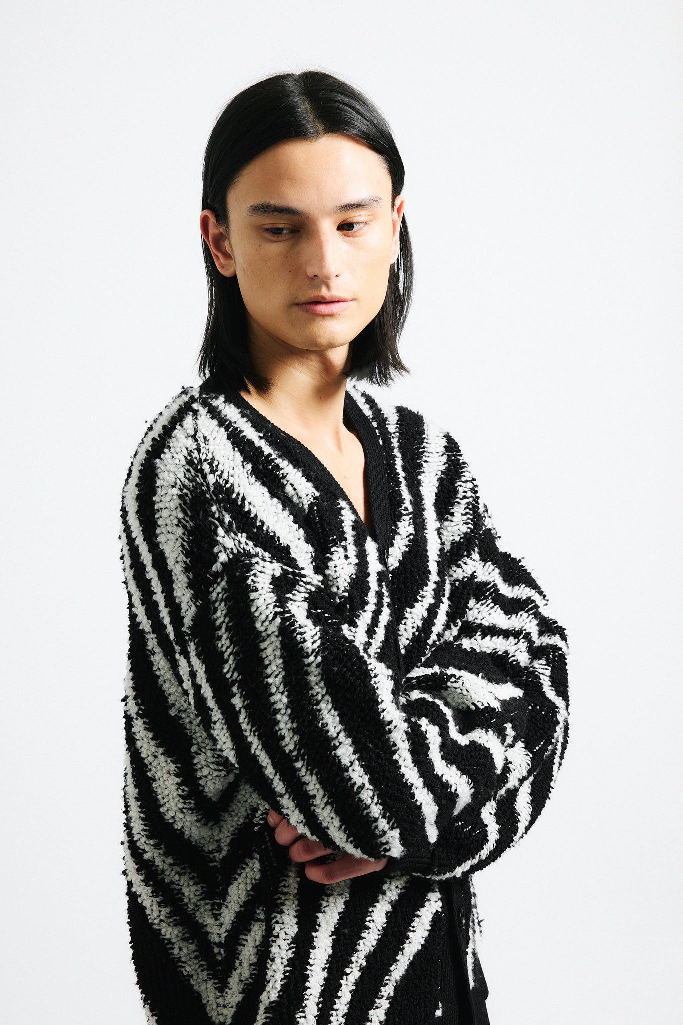 Link to "Christian" cardigan. Image is of a male model wearing "oil spill"/"zebra" print fuzzy v-neck cardigan in black and white stripes with black shorts.