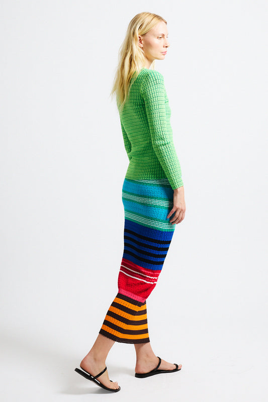 Link to "Edith" fitted skirt. Image is of a female model wearing green vertical ribbed fitted V-neck cardigan with pointelle texture and matching textured bright multi-colored long fitted knit skirt. 