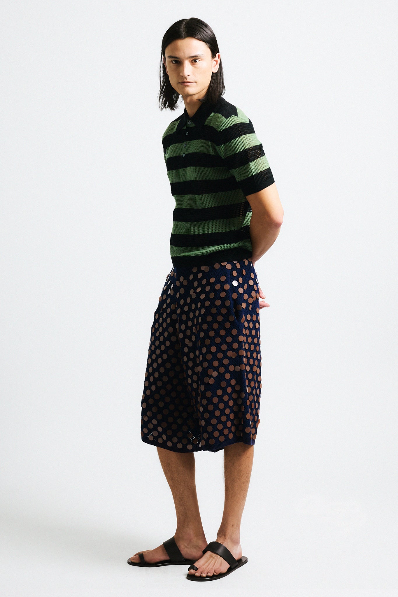 Link to "Luke" polo. Image is of a male model wearing green and black perforated stripe polo shirt and navy black/brown sequin knit shorts.