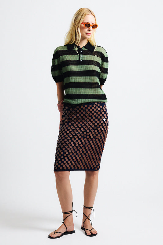 Link to "Matteo" skirt. Image is of a female model wearing green and black perforated stripe polo shirt and navy black/brown sequin knit skirt.